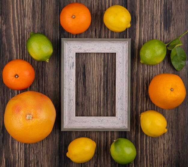 Vue de dessus copie espace pamplemousse avec oranges citron vert et cadre gris sur fond en bois