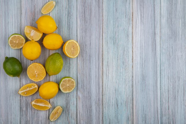 Vue de dessus copiez les citrons de l'espace avec de la chaux et des quartiers sur fond gris