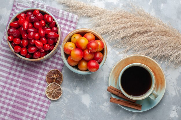 Vue de dessus cornouiller rouge frais avec du thé sur le bureau blanc fruits thé frais mûrs mûrs