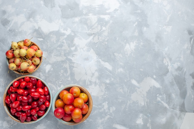 Vue de dessus des cornouillers rouges avec cerises-prunes et cerises sur un bureau léger