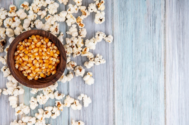 Vue de dessus des cors sur bol en bois avec pop-corn isolé sur gris avec espace copie