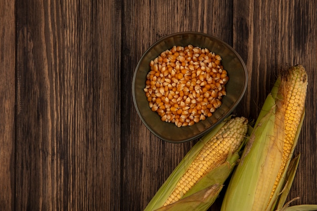 Photo gratuite vue de dessus des cors frais et bio avec des cheveux avec des grains de maïs sur un bol sur une table en bois avec espace copie