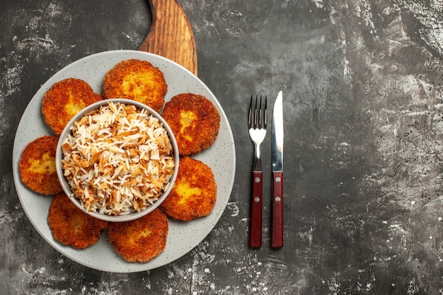 Vue de dessus côtelettes frites avec du riz cuit sur la rissole de viande de plat de surface sombre