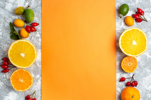 Photo gratuite vue de dessus coupé oranges mandarines chien églantier feijoas nappe orange sur table grise