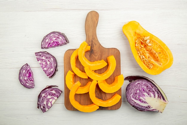 Photo gratuite vue de dessus de la courge musquée au chou rouge coupée en moitié de la courge hachée sur une planche à découper sur une table grise