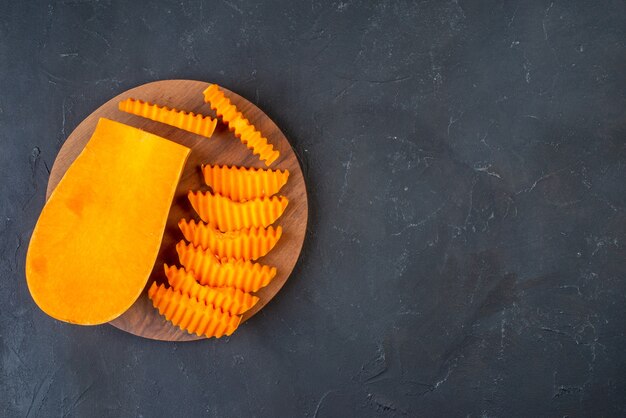 Photo gratuite vue de dessus de la courge musquée hachée avec un couteau en zigzag sur une planche de bois sur une table avec place libre