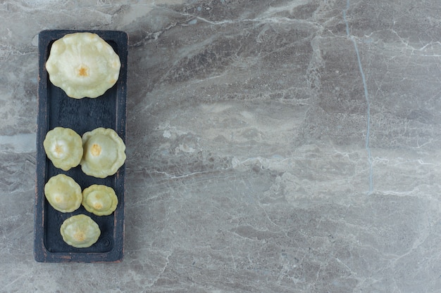 Vue de dessus de la courge verte au cornichon sur une planche de bois noire.