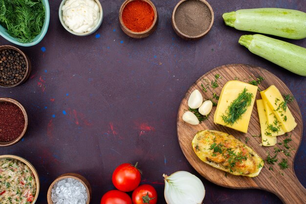 Vue de dessus des courges cuites au four avec assaisonnements verts au fromage, viande hachée et légumes frais sur un bureau violet foncé.