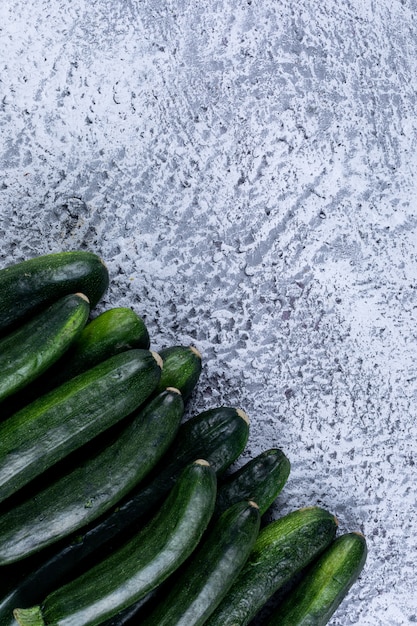 Photo gratuite vue de dessus des courgettes fraîches sur une table texturée grise.