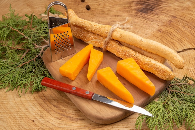 Vue de dessus couteau à fromage et à pain petite râpe à boîte sur planche à découper branches de pin