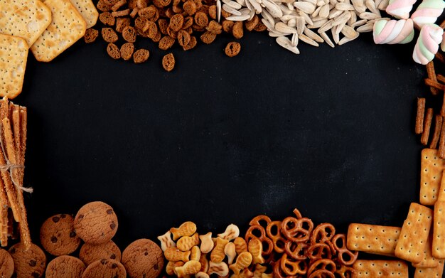 Vue de dessus des crackers avec des biscuits biscuits et des graines sur un fond noir