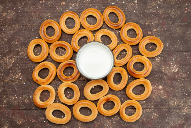 Vue de dessus des craquelins ronds sucrés secs avec un verre de lait froid sur brun, biscuit biscuit boire du sucre sucré croustillant