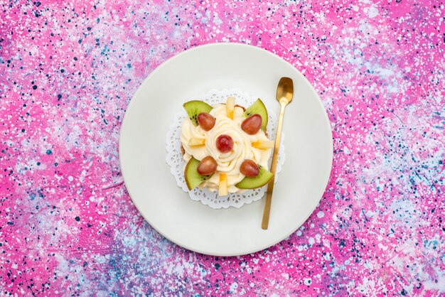 Vue de dessus de la crème de gâteau avec des fruits frais tranchés à l'intérieur de la plaque sur le fond coloré gâteau biscuit couleur douce