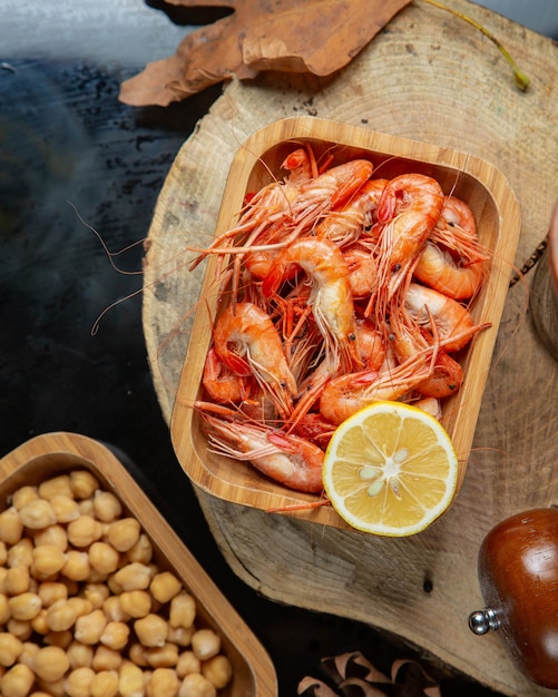 Vue de dessus des crevettes bouillies servies avec du citron dans une portion de bambou