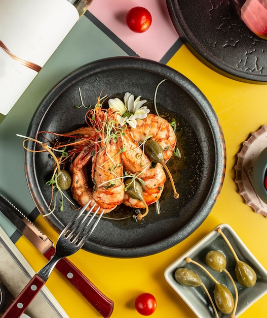 Vue de dessus de crevettes grillées garnies de cornichons et de fleurs