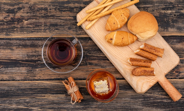 Vue de dessus des croissants avec du thé et du miel sur une surface en bois sombre horizontal