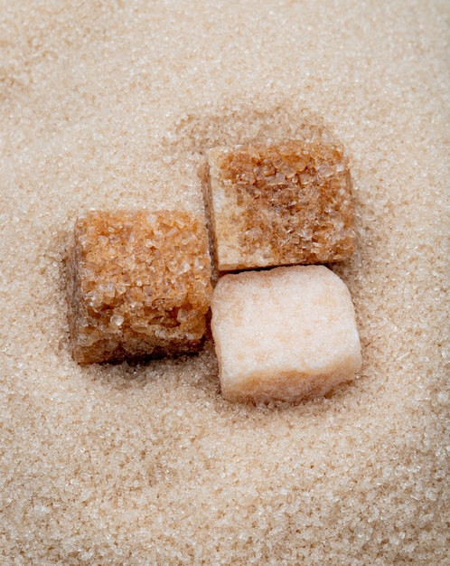 Vue de dessus des cubes de sucre brun sur fond de sucre granulé