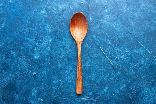 Vue de dessus cuillère en bois sur place de copie de table bleue