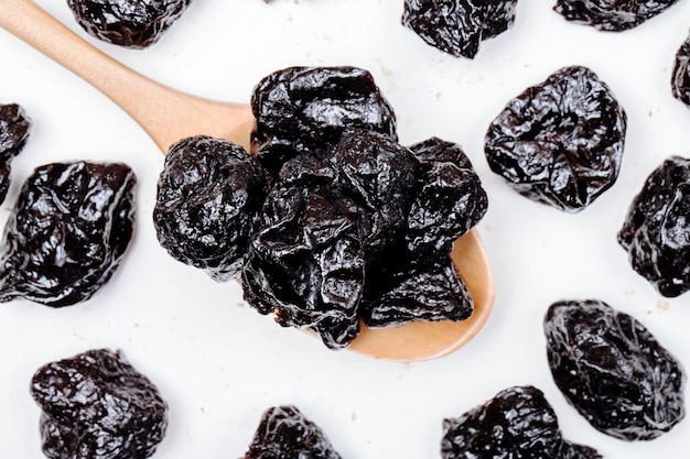 Vue de dessus d'une cuillère en bois avec pruneaux séchés prunes sur fond blanc