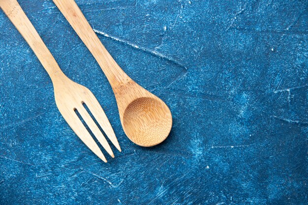 Vue de dessus cuillère fourchette en bois sur place libre de table bleue