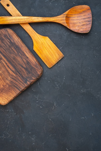 Vue de dessus des cuillères en bois de planche de bois sur un lieu de copie de table sombre