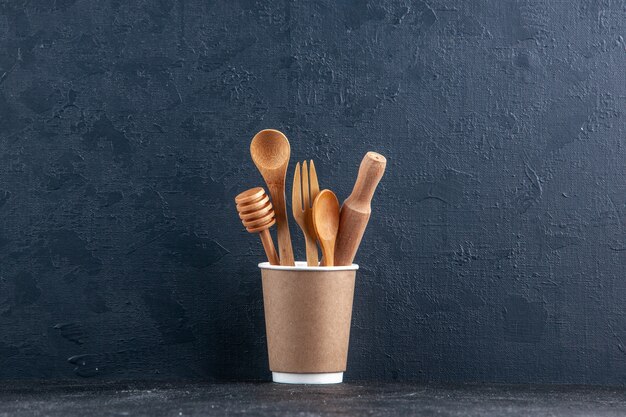 Vue de dessus des cuillères de cuisine en bois dans une cafetière en plastique sur un mur sombre