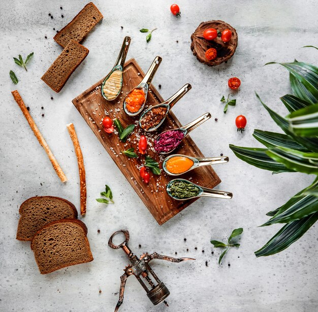 Vue de dessus des cuillères de diverses sauces sur fond gris