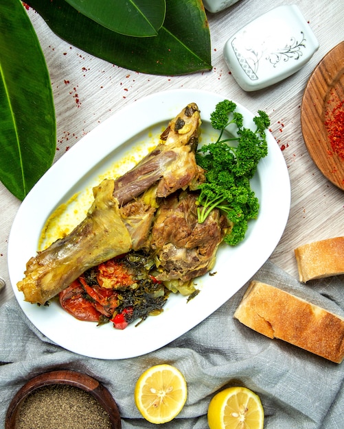 Photo gratuite vue de dessus cuisse d'agneau bouillie avec légumes aux épices tranches de citron et pain