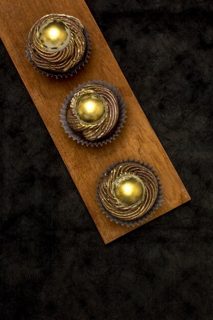 Vue de dessus des cupcakes dorés sur planche de bois