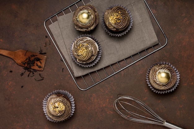 Vue de dessus des cupcakes sur une grille de refroidissement avec fouet et spatule