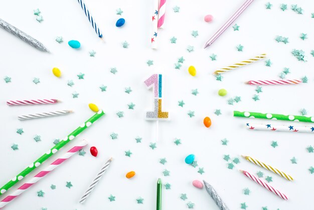 Une vue de dessus des décorations d'anniversaire de bougies et de bonbons sur un bureau blanc, fête d'anniversaire