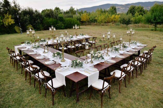 Vue de dessus décorée de bouquets de fleurs minimalistes table de célébration de mariage avec des sièges chiavari à l'extérieur dans les jardins avec vue sur la montagne