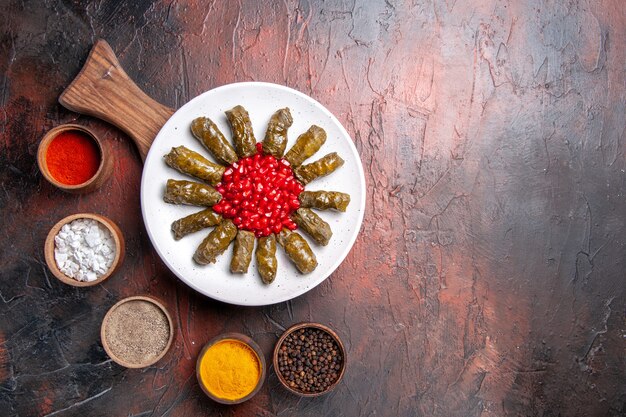 Vue de dessus de la délicieuse feuille de dolma avec des assaisonnements sur une surface sombre