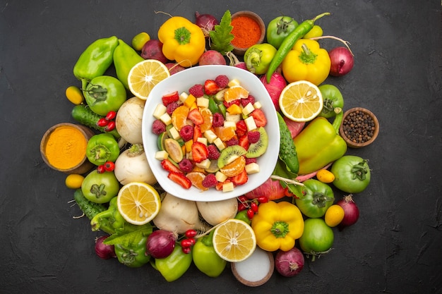 Vue de dessus une délicieuse salade de fruits à l'intérieur de la plaque avec des fruits frais sur un arbre fruitier gris photo tropicale exotique régime mûr