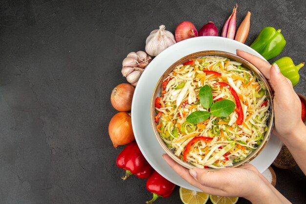 Vue de dessus délicieuse salade de légumes avec assaisonnements et légumes frais sur fond gris