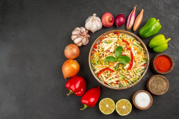 Vue de dessus délicieuse salade de légumes avec assaisonnements et légumes frais sur fond gris