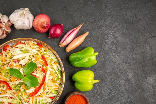 Vue de dessus délicieuse salade de légumes avec assaisonnements et légumes frais sur fond gris