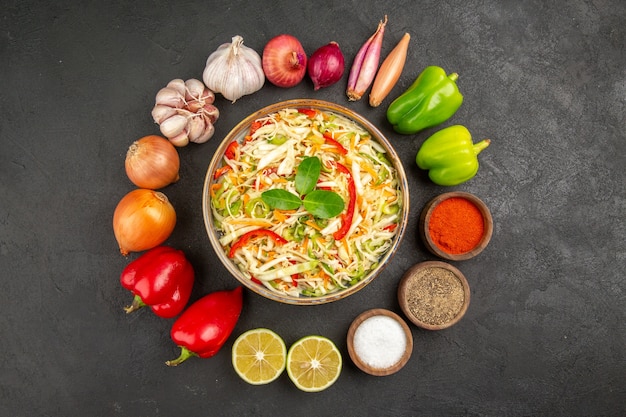 Vue de dessus délicieuse salade de légumes avec assaisonnements et légumes frais sur fond gris