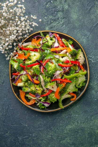 Vue de dessus d'une délicieuse salade de légumes avec divers ingrédients sur une planche à découper noire