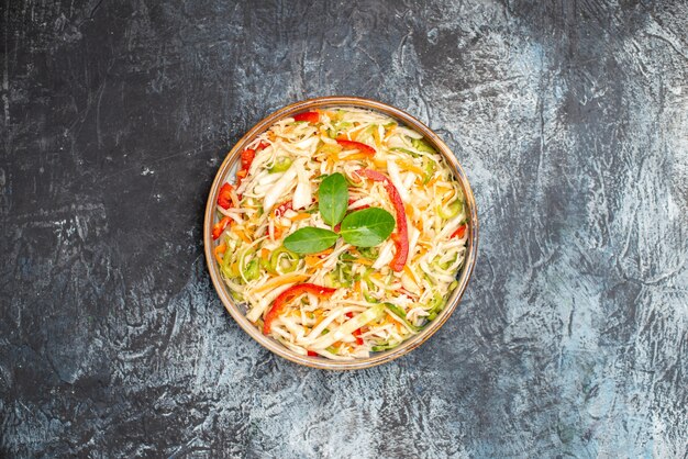 Vue de dessus délicieuse salade de légumes à l'intérieur du plateau sur fond gris