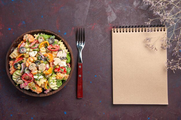 Vue de dessus une délicieuse salade de légumes avec des tomates, des olives et des champignons sur le fond sombre régime santé salade légume déjeuner collation