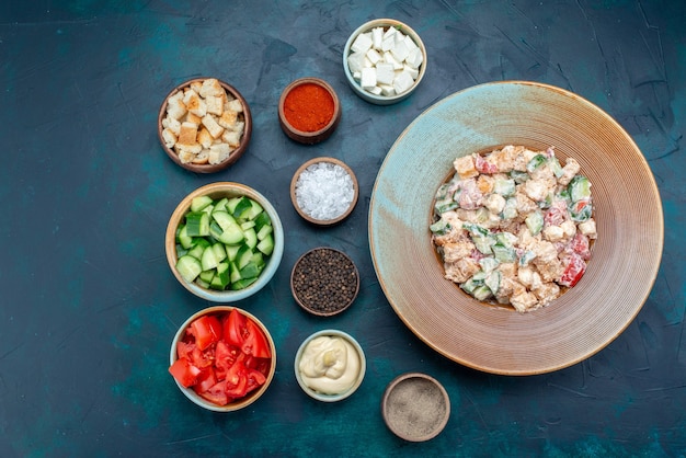 Vue de dessus de la délicieuse salade mayyonaised à l'intérieur de la plaque avec des légumes tranchés sur le bureau bleu repas alimentaire salade de légumes