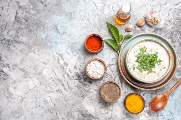 Vue de dessus délicieuse soupe au yaourt dovga avec assaisonnements sur un plat blanc lait de soupe lait