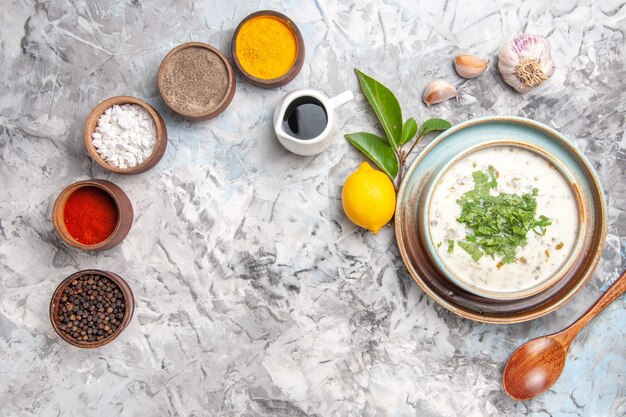 Vue de dessus délicieuse soupe au yaourt dovga avec assaisonnements sur un plat de soupe au lait blanc