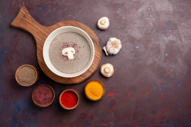 Vue de dessus délicieuse soupe aux champignons avec des assaisonnements sur un espace sombre