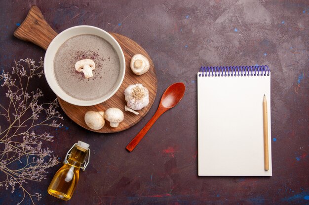 Vue de dessus délicieuse soupe aux champignons avec des champignons frais et de l'huile sur un bureau sombre