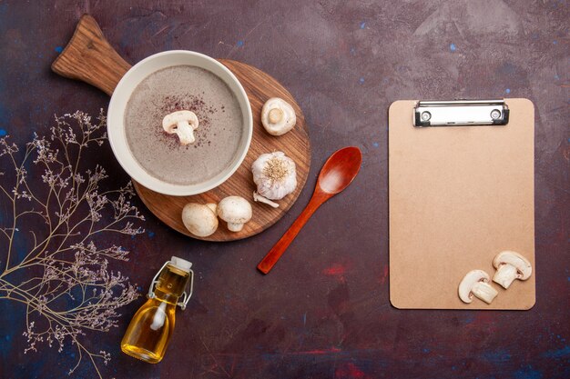 Vue de dessus délicieuse soupe aux champignons avec des champignons frais et de l'huile sur un bureau sombre