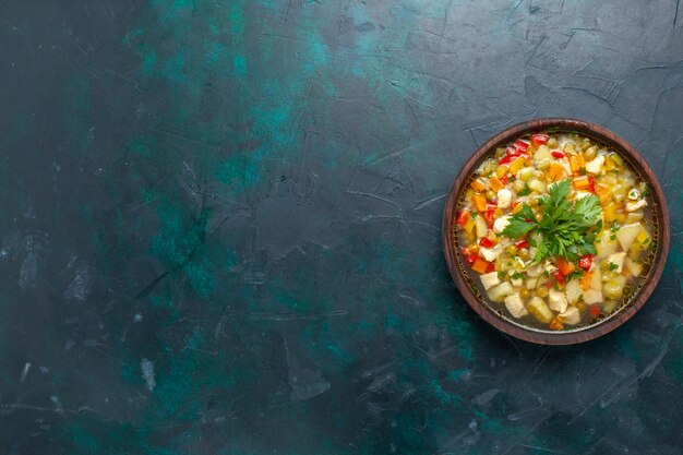 Vue de dessus délicieuse soupe aux légumes avec différents ingrédients à l'intérieur du pot brun sur le bureau sombre soupe sauce aux légumes repas nourriture chaude