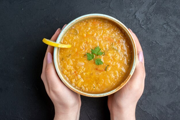 Vue de dessus délicieuse soupe aux lentilles avec plaque de maintien femme miches de pain noir sur une surface sombre