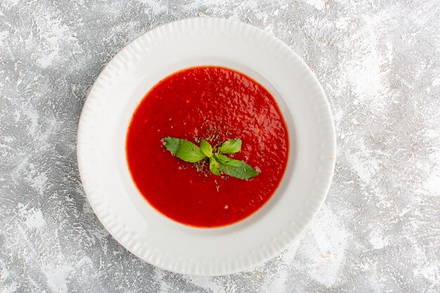 Vue de dessus délicieuse soupe aux tomates avec assaisonnements sur table grise, soupe repas dîner légume